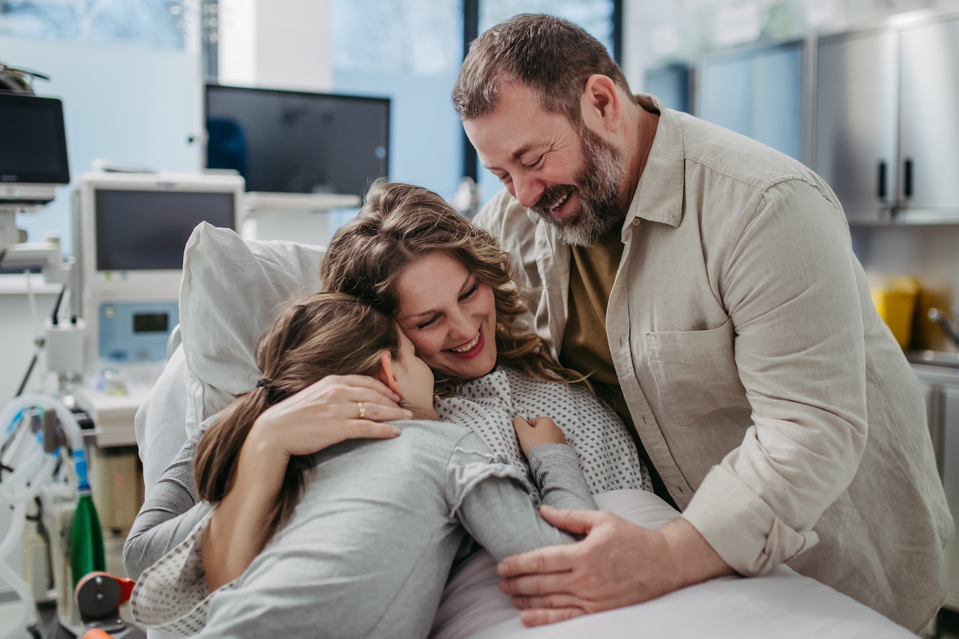 Father and daughter visiting mother in hospital after surgery. Emotional support from family for patients in hospital.